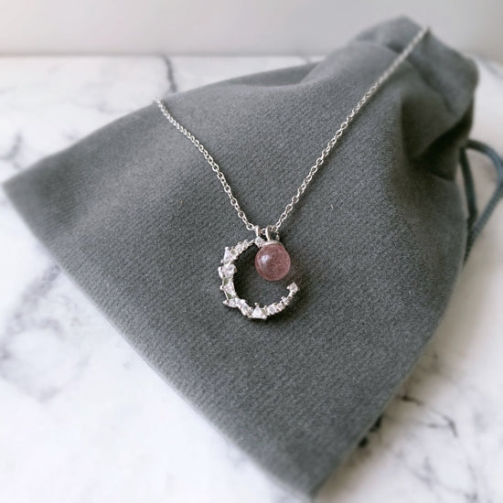 Introducing our stunning Strawberry Crystal Moon Pendant Necklace, handcrafted with natural Strawberry Quartz and a crystal Moon pendant, hanging on a Sterling Silver Chain. This unique necklace is the perfect addition to any jewellery collection and is sure to turn heads.